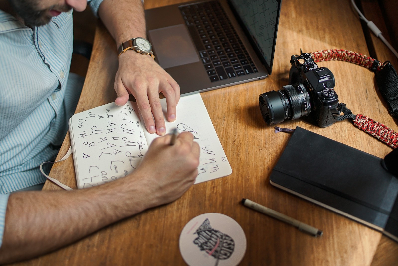 Designer sketching logo concepts in a notebook beside a laptop